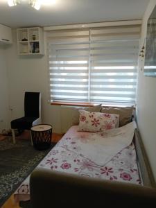 a bed in a room with a window and a chair at Dimitra Stan na dan in Šabac