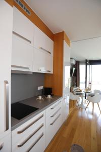 a kitchen with white cabinets and a dining table at BL Waterside 55 in Balatonlelle
