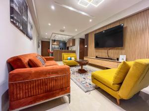 a living room with yellow chairs and a television at Solaris Luxury Residence Osu Pool Gym in Accra
