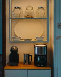 a shelf with cups and dishes and a coffee maker at R&M Ocean View in Dhaskalión