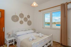 a white bedroom with a bed and a window at R&M Ocean View in Dhaskalión