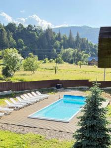 a pool with chaise lounge chairs and a tree at Kozarik in Mykulychyn