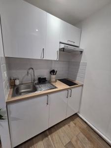 a small kitchen with white cabinets and a sink at Studio cosy devant RER B TGV Massy SNCF in Massy