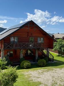 a large log house with a porch and a deck at Kozarik in Mykulychyn