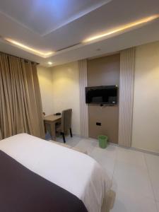 a bedroom with a bed and a desk and a television at CHASE hotels in Ibadan