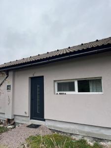 a white house with a blue door and two windows at Útulný 1kk byt in Líšnice