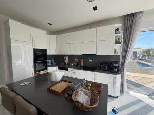 a kitchen with white cabinets and a table with a bowl of fruit at Villa Berisha in Mazgit