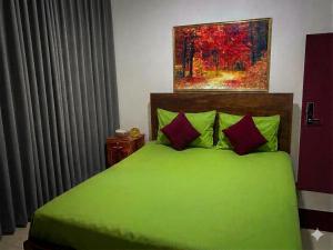a bedroom with a green bed with a painting on the wall at The White Grand Heritage in Balangoda