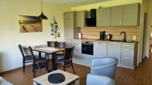 a kitchen and dining room with a table and chairs at Boddenhof Apartment 52 - Balkon, hundefreundlich in Buschvitz +9 photos