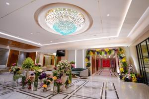 a lobby with a large chandelier and flowers in vases at Hotel Shubham Celebrations-Miyapur in Lingampalli