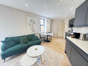 a living room with a green couch and a table at Stylish City Centre Flat - Walk to Trinity & Station in Leeds