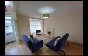 a living room with two blue chairs and a television at Anghorfa in Llanberis