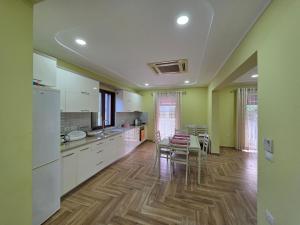 a kitchen with white cabinets and a table and chairs at N'Gegaj Villa in Shkodër