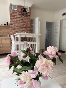 a vase filled with pink flowers sitting on a table at Parka ielas apartamenti in Limbaži