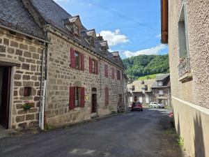 an alley in a medieval town with red shutters at Le Randonneur in Fontanges