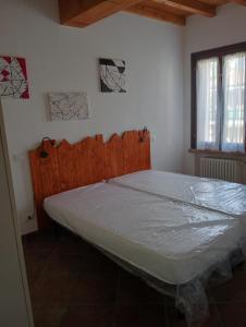 a bedroom with a large bed with a wooden headboard at Casa LB14 in Castelletto Borgo