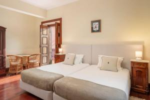 a bedroom with a large white bed and a table at Casa da Fajã Alta in São Jorge