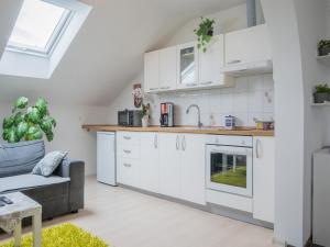 a kitchen with white cabinets and a gray couch at Apartments Bukor with seasonal pool in Lukovica pri Domžalah