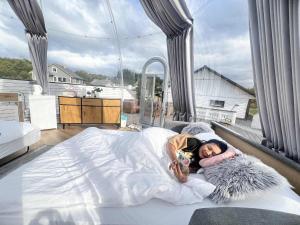 a woman laying on a bed in a room with a large window at Banpim Aroradome and jacusszy in Gravdal