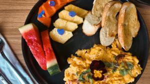 a black plate of food with eggs and fruit at Hotel Ryo 74B Suites by Growing Group in Medellín