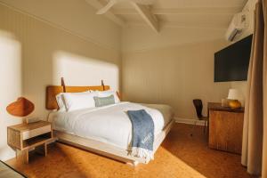 a bedroom with a large white bed and a television at Barlume Beach in Montauk