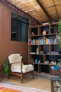a living room with a chair and a book shelf at Colibri Wasi Pisac in Cusco