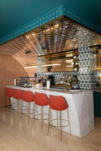 a bar with red chairs in front of a counter at Kimpton Vividora Hotel by IHG in Barcelona +278 photos