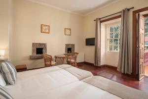 a bedroom with a bed and a table and chairs at Casa da Fajã Alta in São Jorge