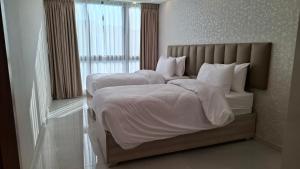 ein Schlafzimmer mit zwei Betten mit weißer Bettwäsche und einem Fenster in der Unterkunft فندق جواهر العبدلي - Jawaher Hotel in Amman