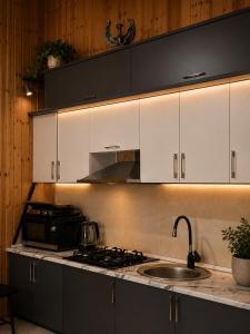 a kitchen with white cabinets and a stove and a sink at Alis House 3 in Batumi +3 photos