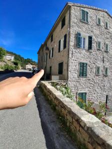 a hand pointing at a stone building at Santoni House in Ghisoni +1 photo