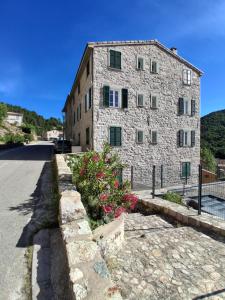a stone building with flowers in front of a street at Santoni House in Ghisoni