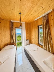 two beds in a room with two windows at Alis House 3 in Batumi