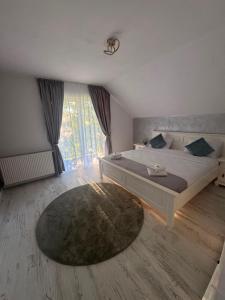 a bedroom with a large bed and a large window at Casa din Frasin in Poiana Mărului