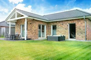 a brick house with a patio and a lawn at Salz & Seele Das Spa Ferienhaus mit Whirlpool, Sauna & Wallbox in Büsum