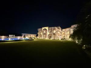 a large white house at night with a palm tree at Oryana Resort in Udaipur