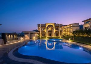 a large house with a large swimming pool in front of it at Oryana Resort in Udaipur