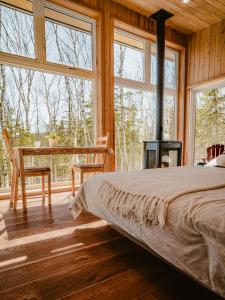 a bedroom with a bed and a table and windows at Tanières MicroChalets Charlevoix in Baie-Saint-Paul