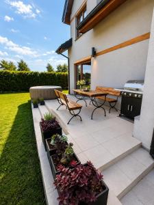 a patio with a table and benches and plants at Morze u Sary - Wrzosowo 361, Dziwnówek in Dziwnówek