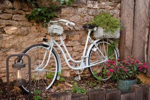 a white bike parked next to a stone wall with flowers at Maison Vitis in Fuissé