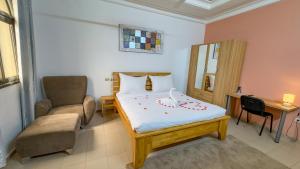 a bedroom with a bed and a chair and a desk at Kipress Lodge Hôtel in Ouagadougou +63 photos