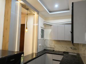 a kitchen with white cabinets and a black counter top at Thecrestoria in Dehradun