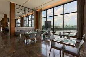 a restaurant with tables and chairs and large windows at Fiesta Inn Mérida Altabrisa in Mérida