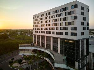 a tall white building with a sunset in the background at Fiesta Inn Mérida Altabrisa in Mérida