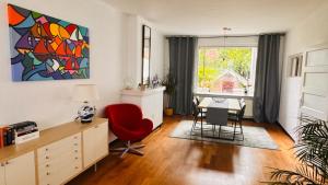 a living room with a desk and a red chair at Light and Spacious Getaway House in Arnhem