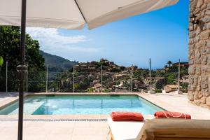 a swimming pool with an umbrella next to a house at Stunning Deià Views & Private Pool in Deia