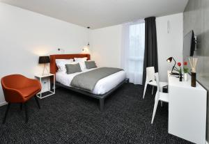 a bedroom with a bed and a desk and a chair at Ténéo Apparthotel Talence Espeleta - Bordeaux Sud in Talence