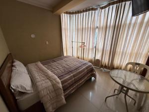 a bedroom with a bed and a table and a window at Hostal Tintaya in Cajamarca