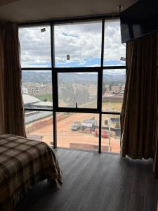 a bedroom with a large window with a view of a field at Hostal Tintaya in Cajamarca