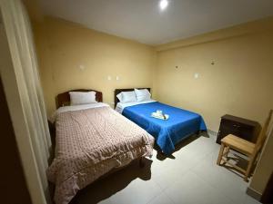 a bedroom with two beds and a blue blanket at Hostal Tintaya in Cajamarca +6 photos